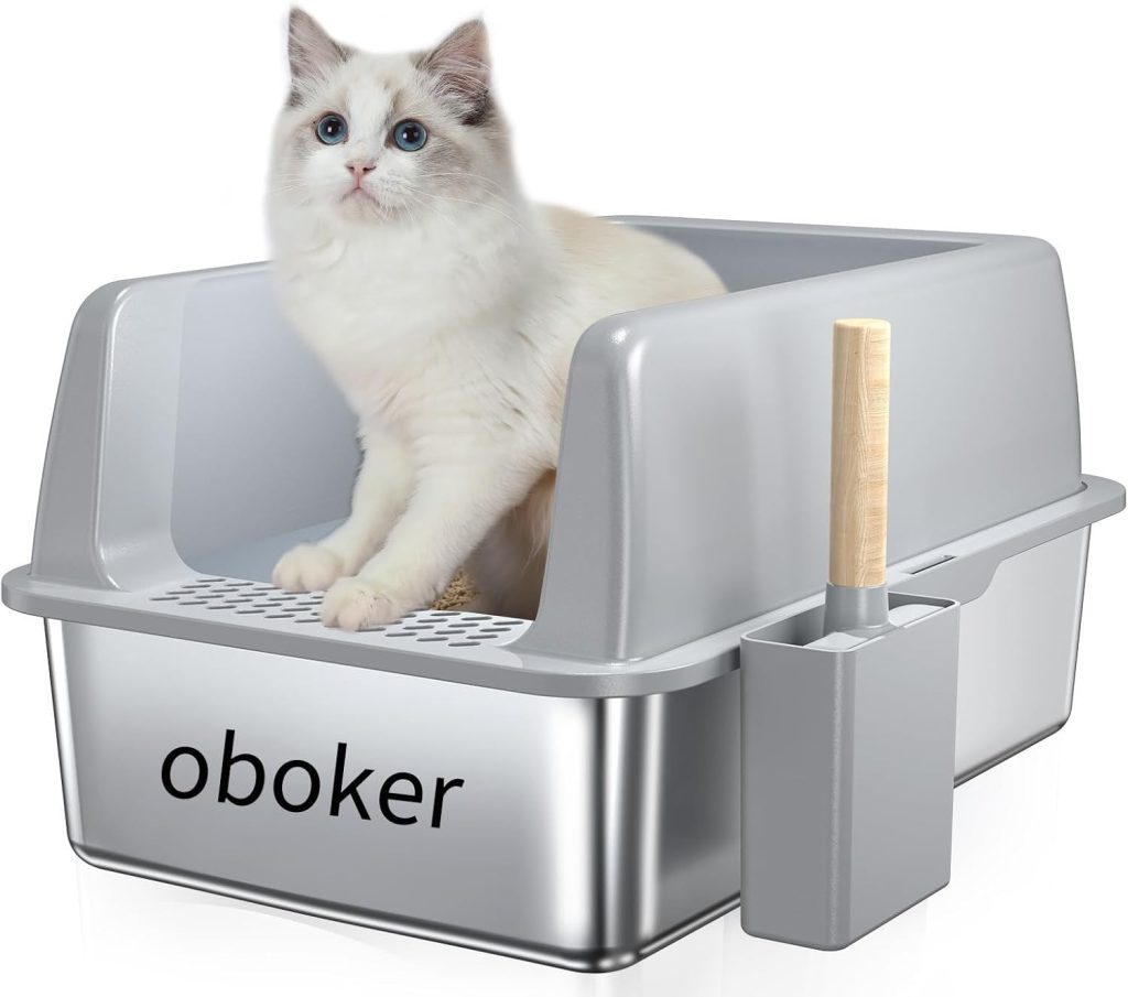 A fluffy white cat with blue eyes sits in a modern, gray litter box labeled "Oboker," equipped with a built-in sifting grate and a matching scoop holder with a wooden-handled scoop